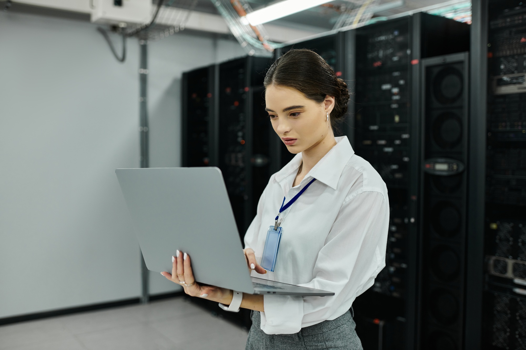 A woman in a white shirt manages a computer system in a high-tech server room.