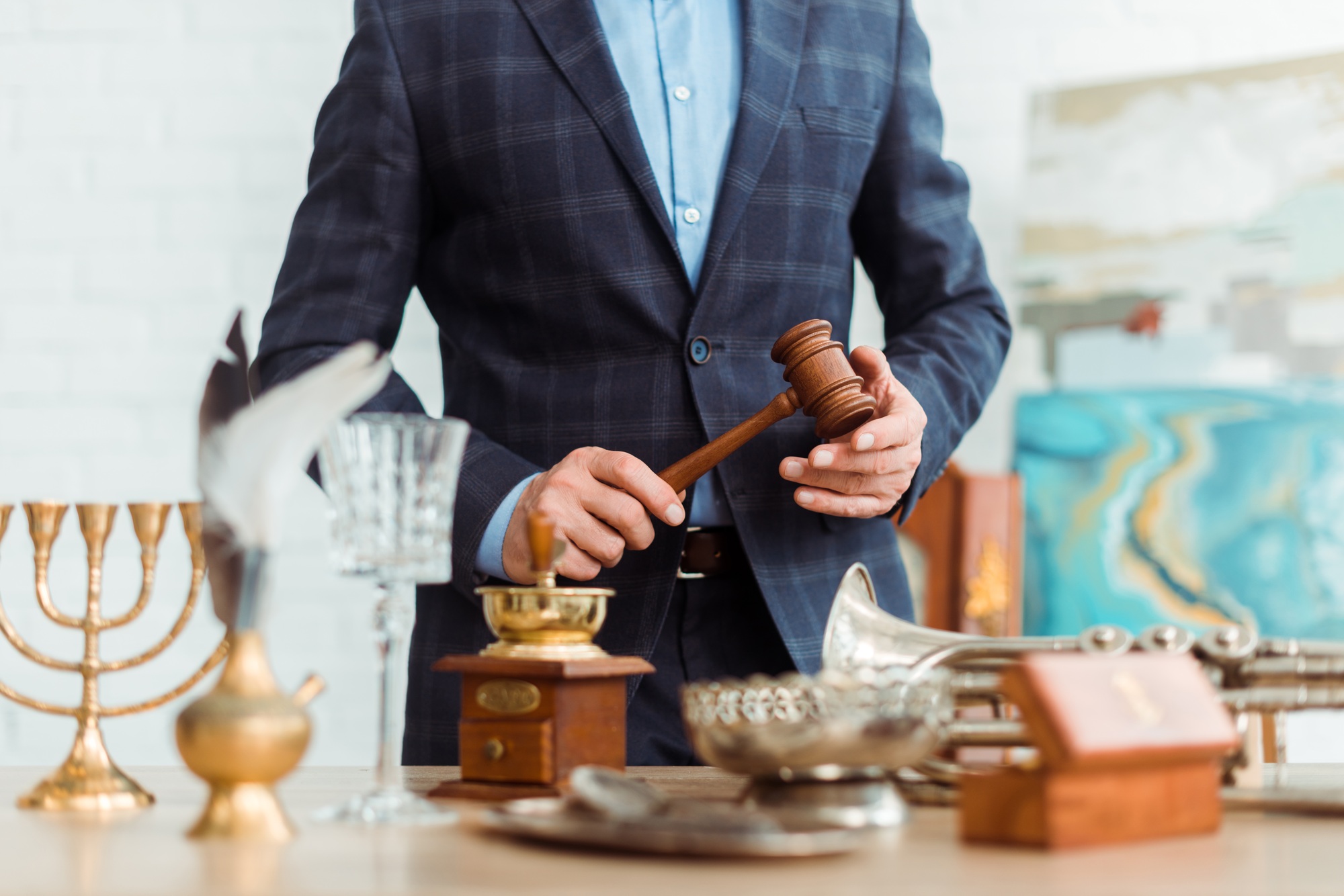 cropped view of auctioneer in suit holding gavel during auction