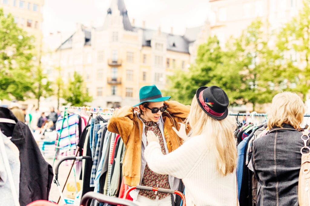 Friend helping young man in wearing jacket at flea market