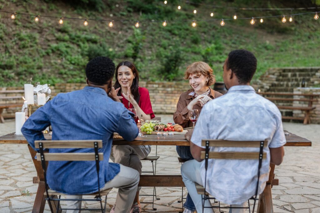 Friends enjoying outdoor dinner party with wine and conversation