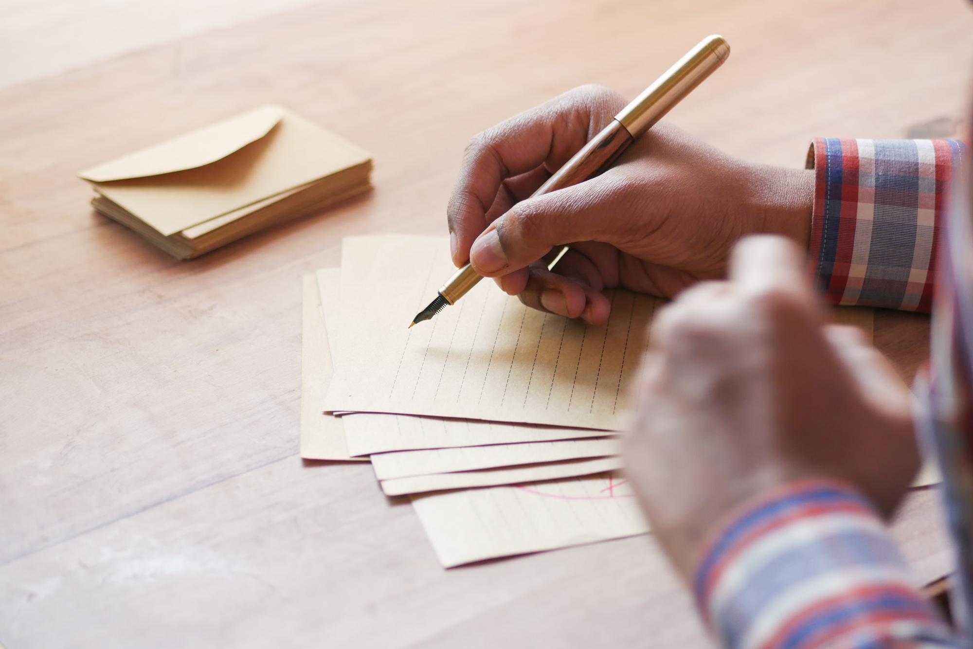 rear view of man writing letter on table