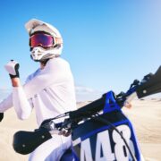 Sports, cycling and man stretching on motorbike on sand for adrenaline, adventure and freedom in de