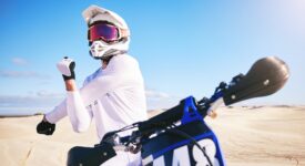 Sports, cycling and man stretching on motorbike on sand for adrenaline, adventure and freedom in de