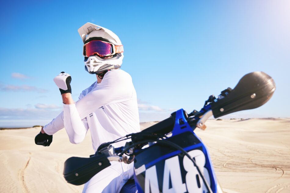 Sports, cycling and man stretching on motorbike on sand for adrenaline, adventure and freedom in de